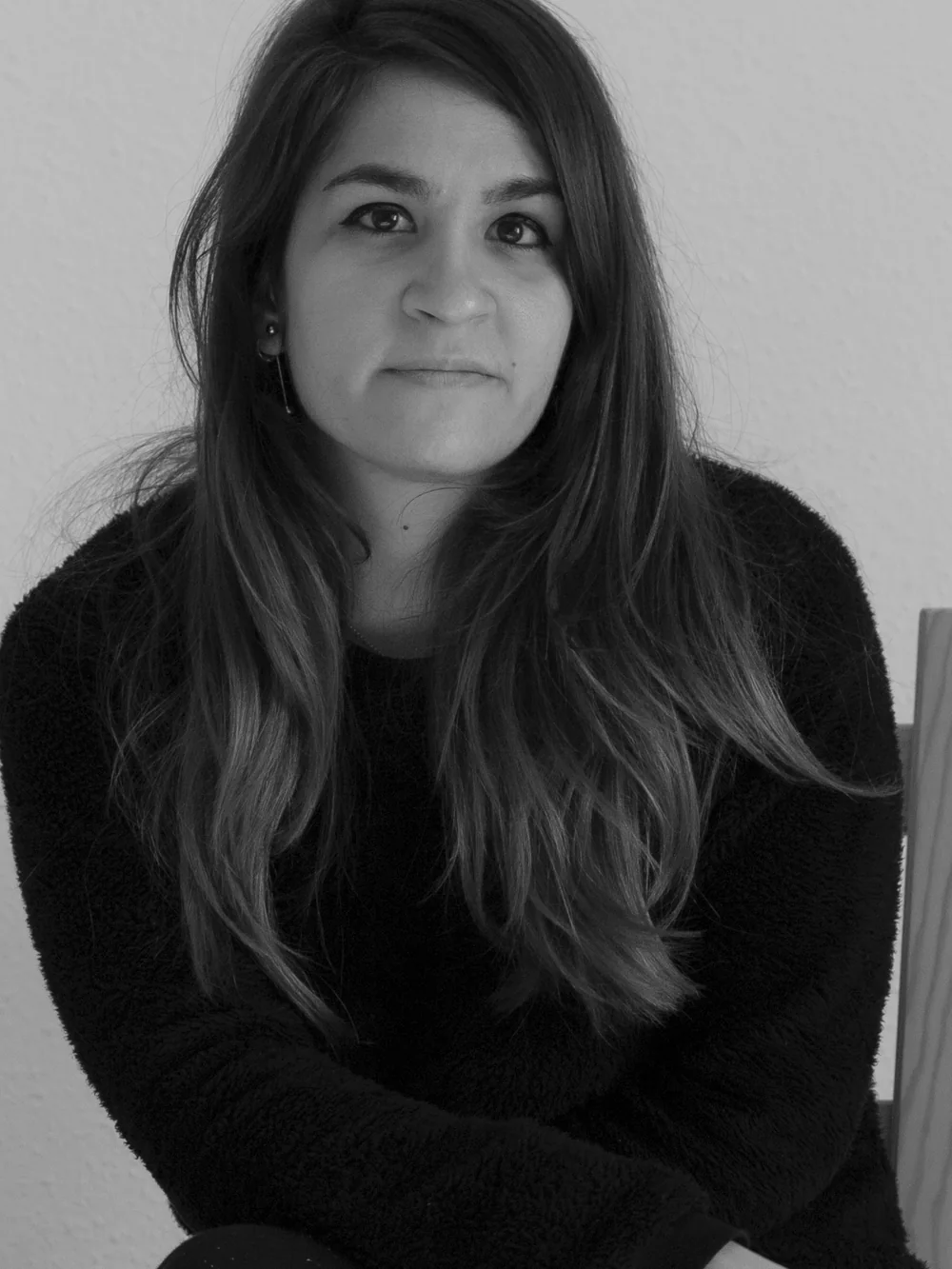 Retrato en blanco y negro de Marta Sánchez sentada en una silla, mirando a cámara.
